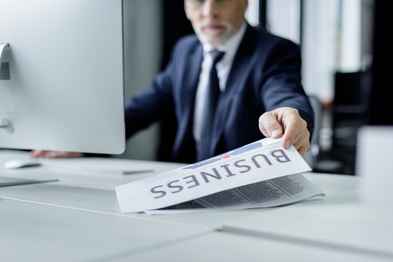 在办公室工作的资深商人拿着报纸