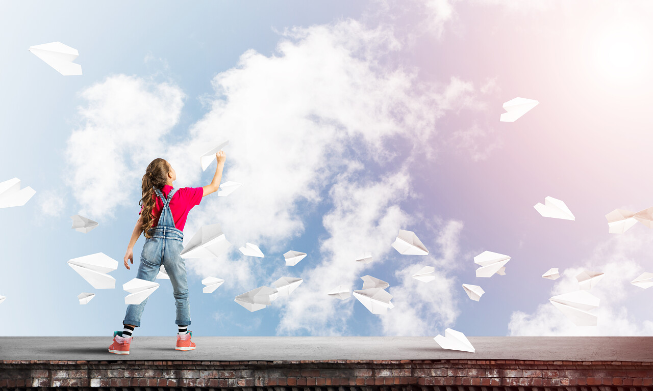 可爱的小女孩在楼顶上玩纸飞机