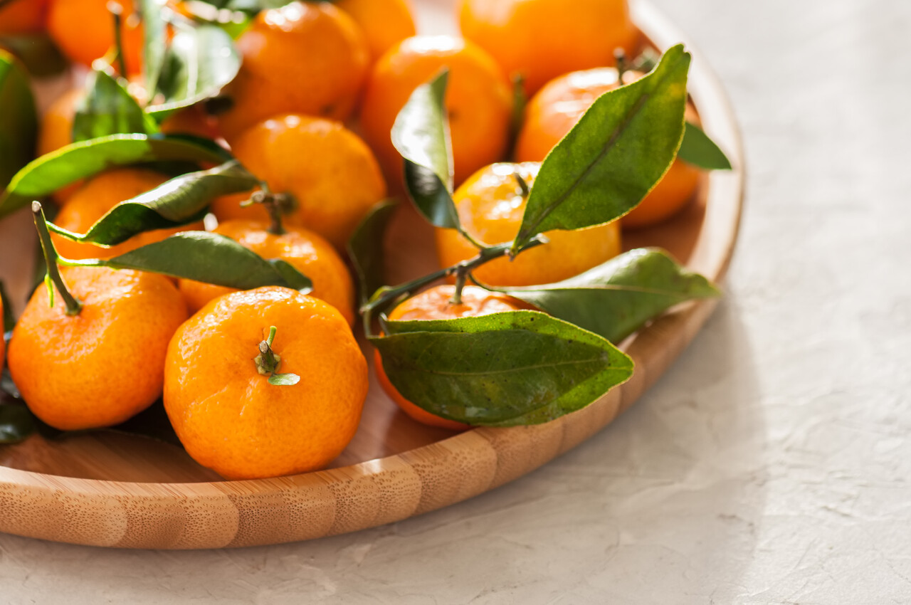 一盘新鲜和多汁的柑橘,叶子在白色的石头背景上