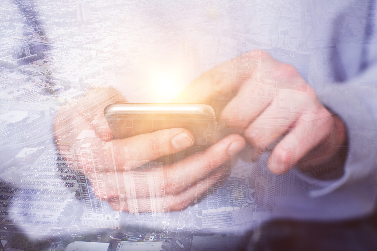 使用手机在抽象发光的夜城市背景的男性手关闭小工具和通信概念