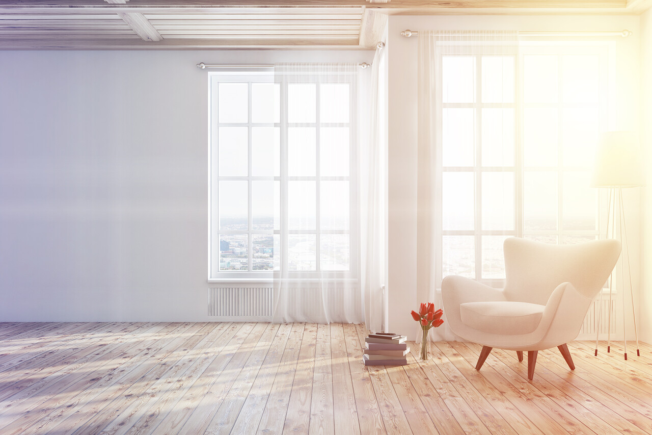 空的白色起居室内部有木地板和高大的窗户和一摞书附近的白色扶手椅