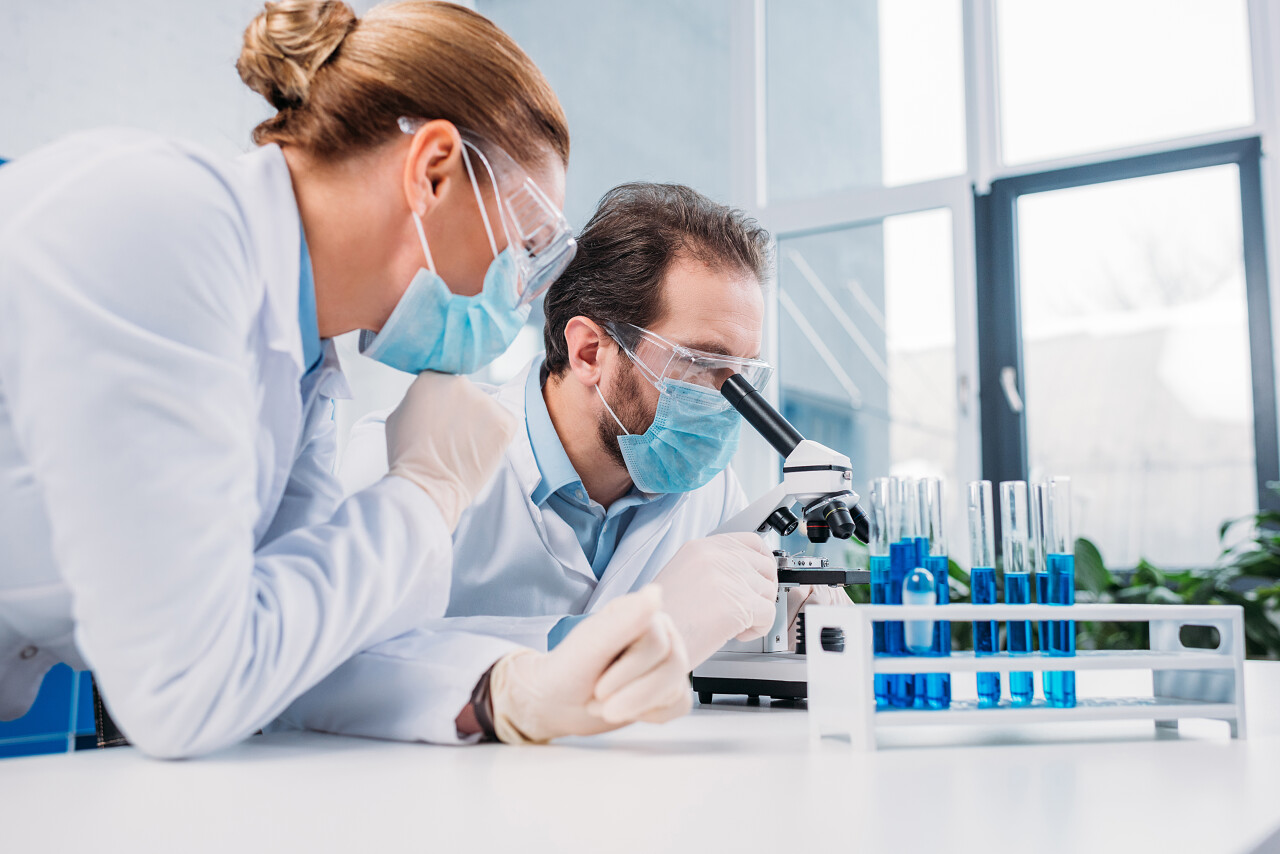 研究人员在白色大衣和医疗口罩一起使用试剂在实验室