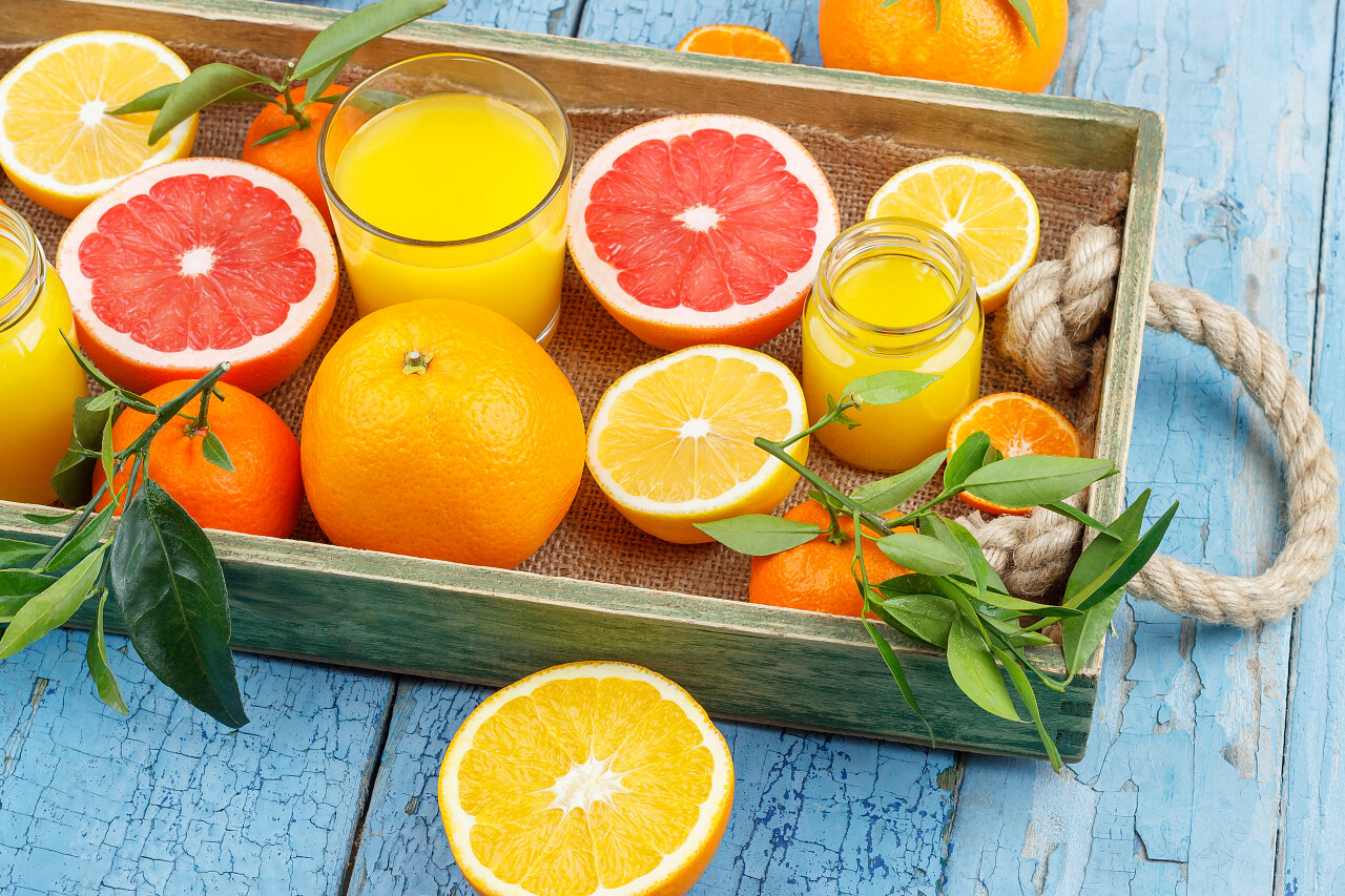 不同的水果和玻璃的新鲜橙汁的木制背景