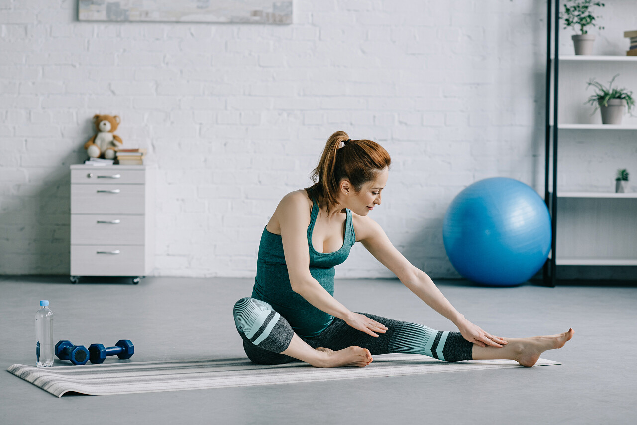 美丽的孕妇在客厅练瑜伽产后瑜伽