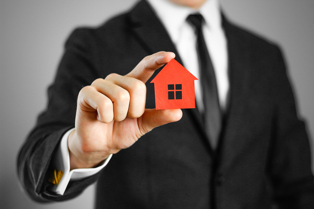 穿黑色西装的男人持有房子的图标