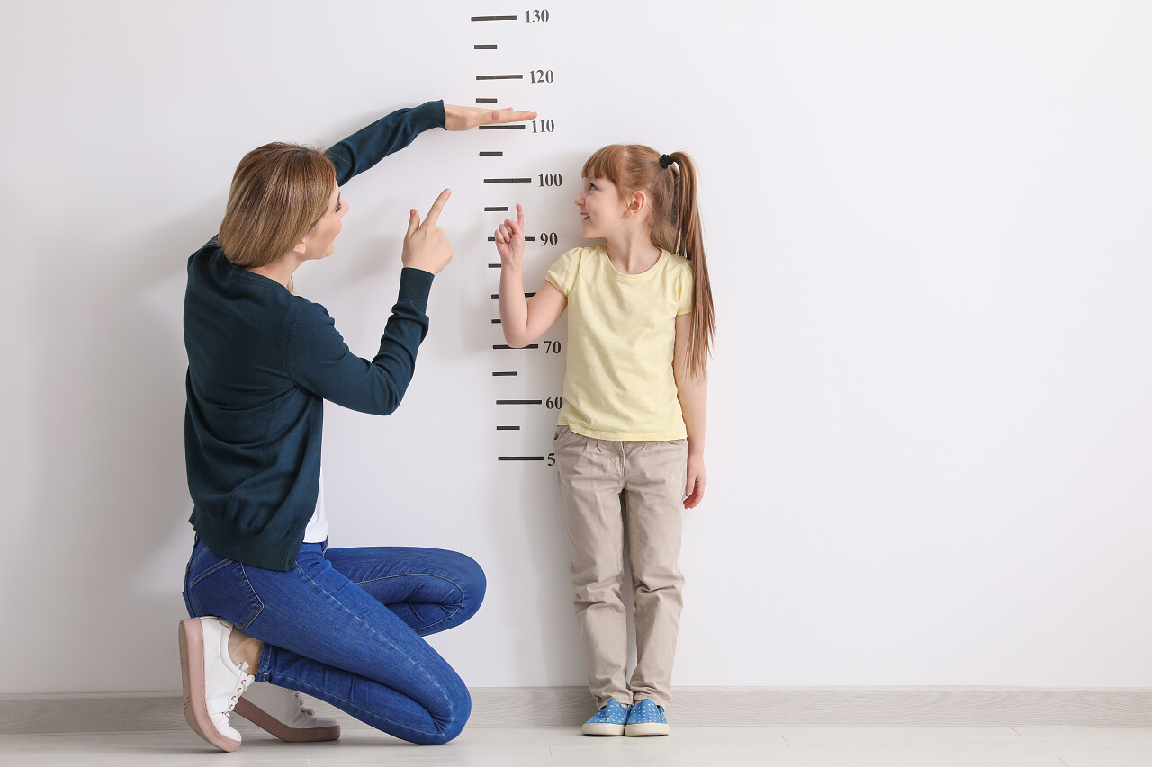 母亲在白墙附近测量女儿的身高