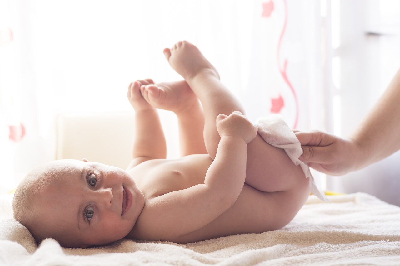 卫生年轻的妈妈用湿纸巾擦拭婴儿皮肤微笑的小孩婴儿微笑