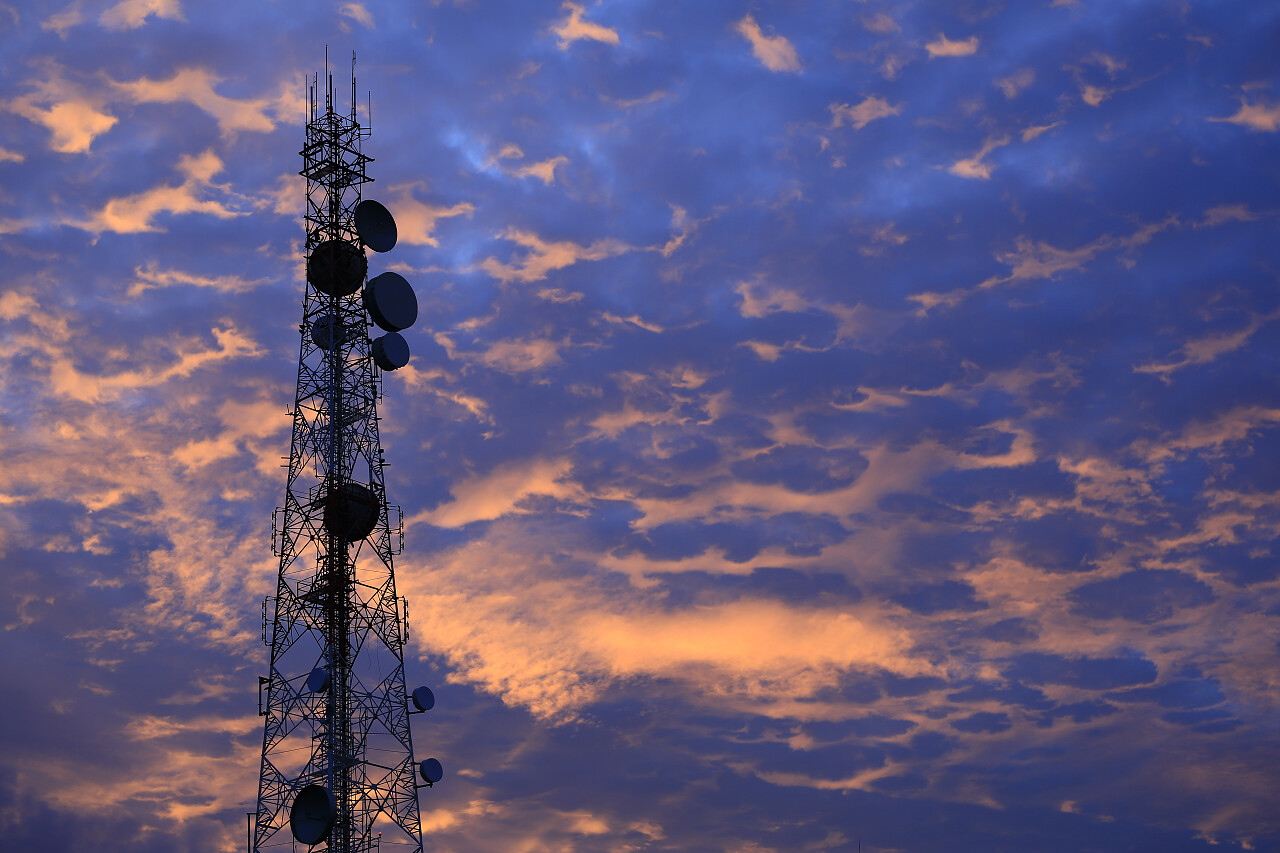 在日落天空背景下的通信塔天线和卫星盘