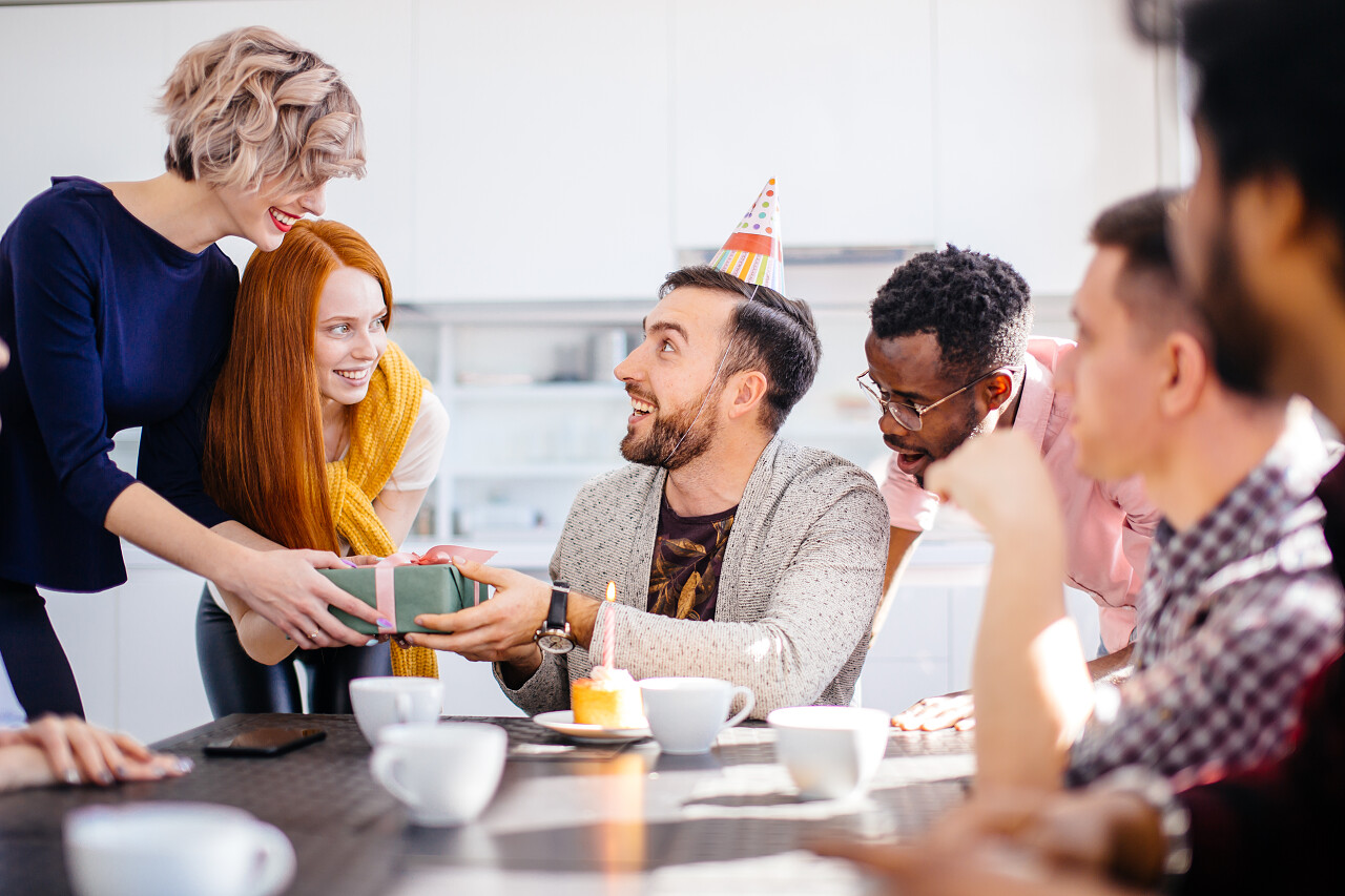 年轻男子戴生日帽得到了员工的礼物团队交流沟通会议
