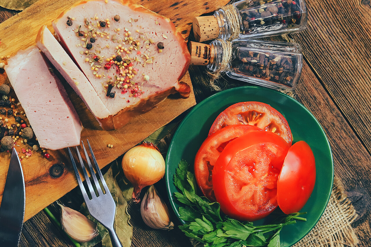 猪肉火腿和香料木制背景的叉子和刀.