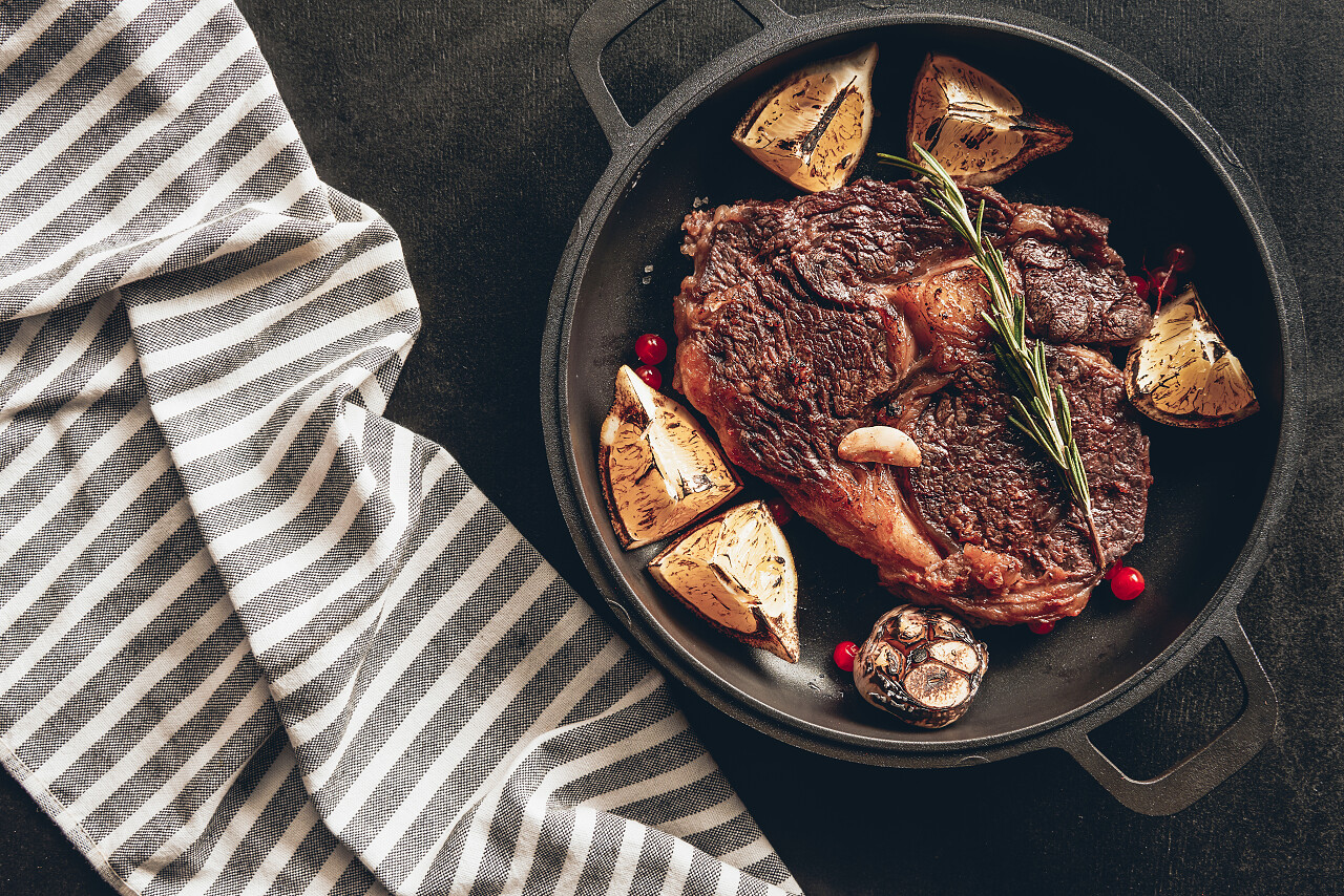 煎锅上的柠檬和浆果熟牛排, 厨房表面桌布西餐牛排