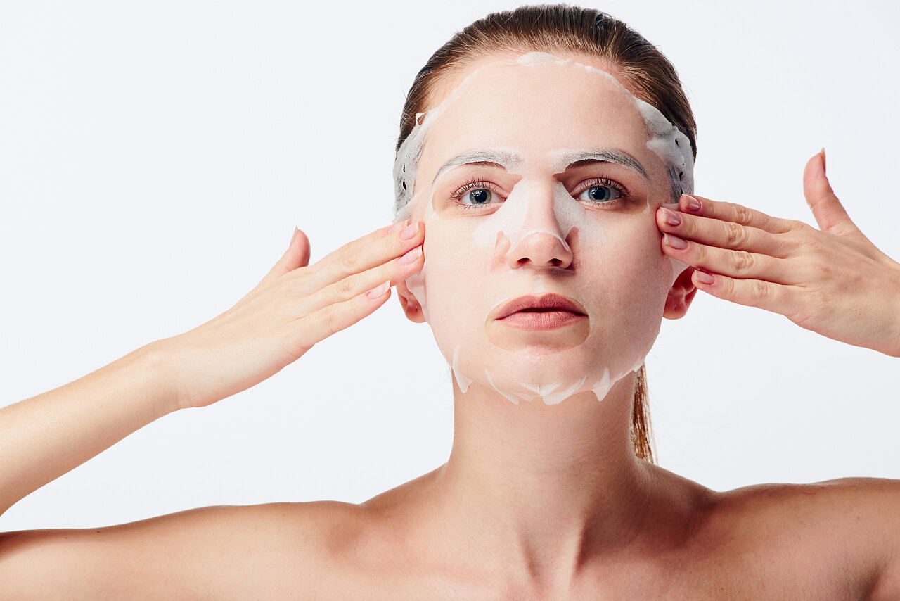 美丽的年轻白种女人在敷面膜面部补水