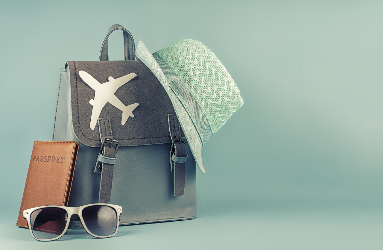 女性时髦的旅游背包与护照和帽子在蓝色背景