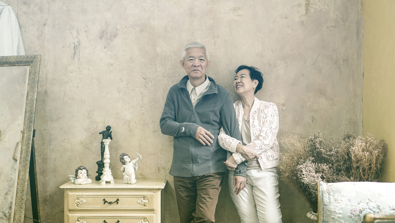 亚洲资深夫妇穿着休闲礼服与太阳镜在复古风格的房子