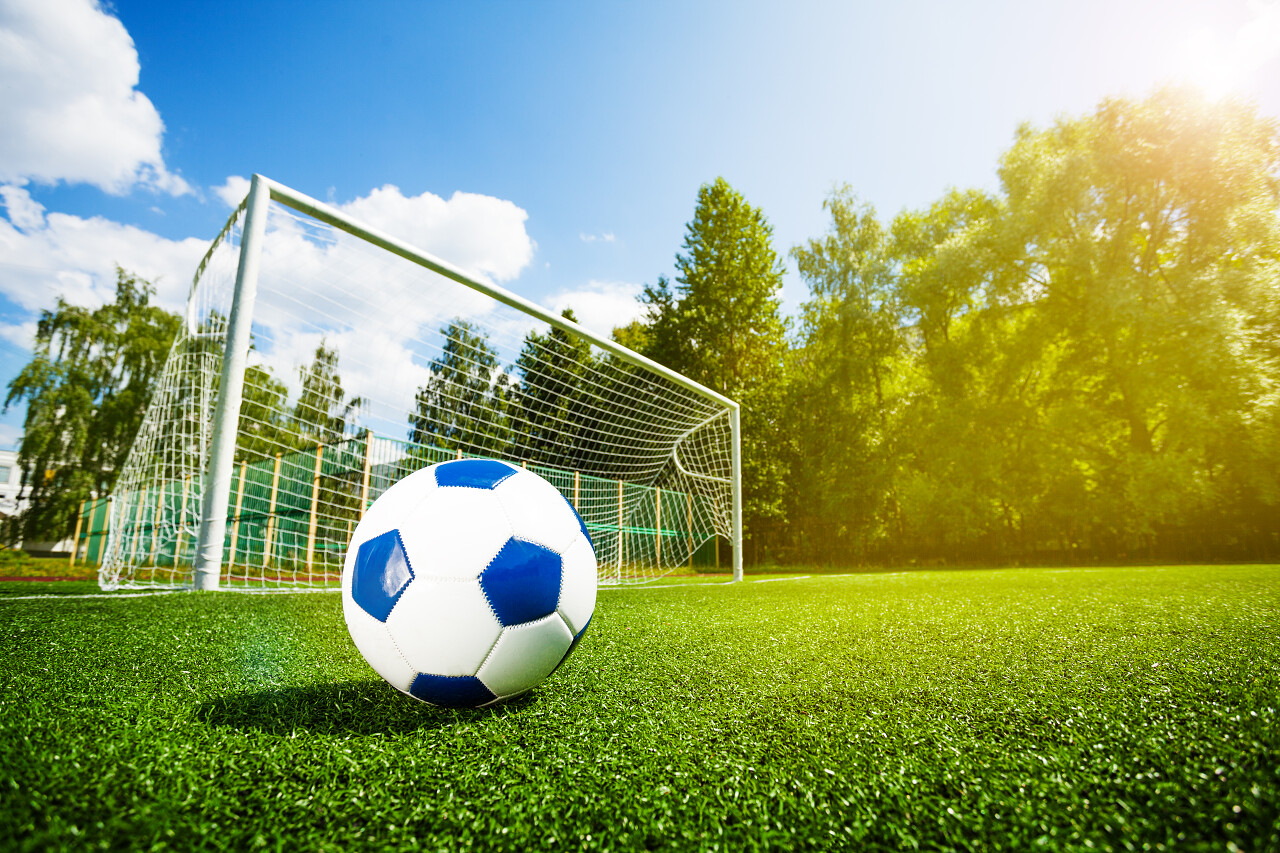 在蓝天的运动场上脚步的足球和大门