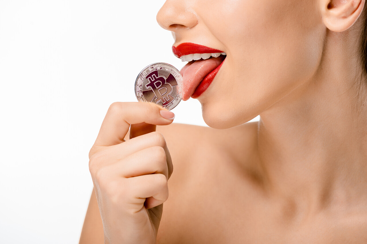 裁剪拍摄的裸体妇女舔比特币孤立在白色