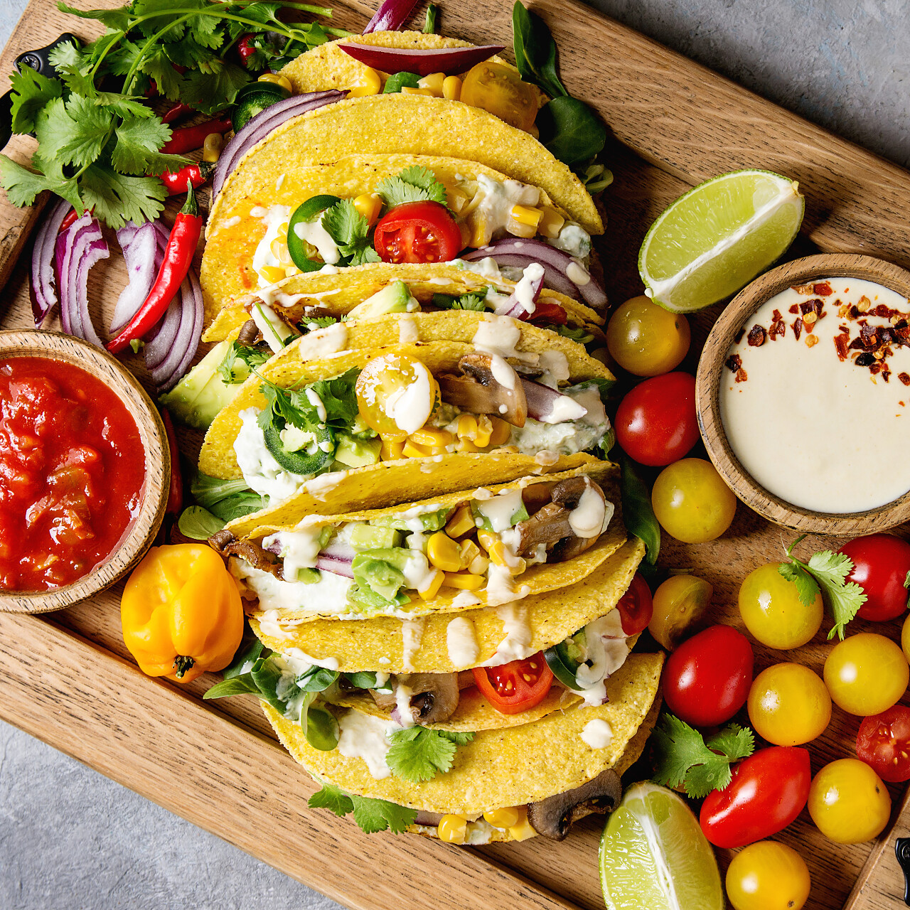 各种素食玉米玉米玉米卷与蔬菜辣椒在木盘上配番茄和奶油酱汁
