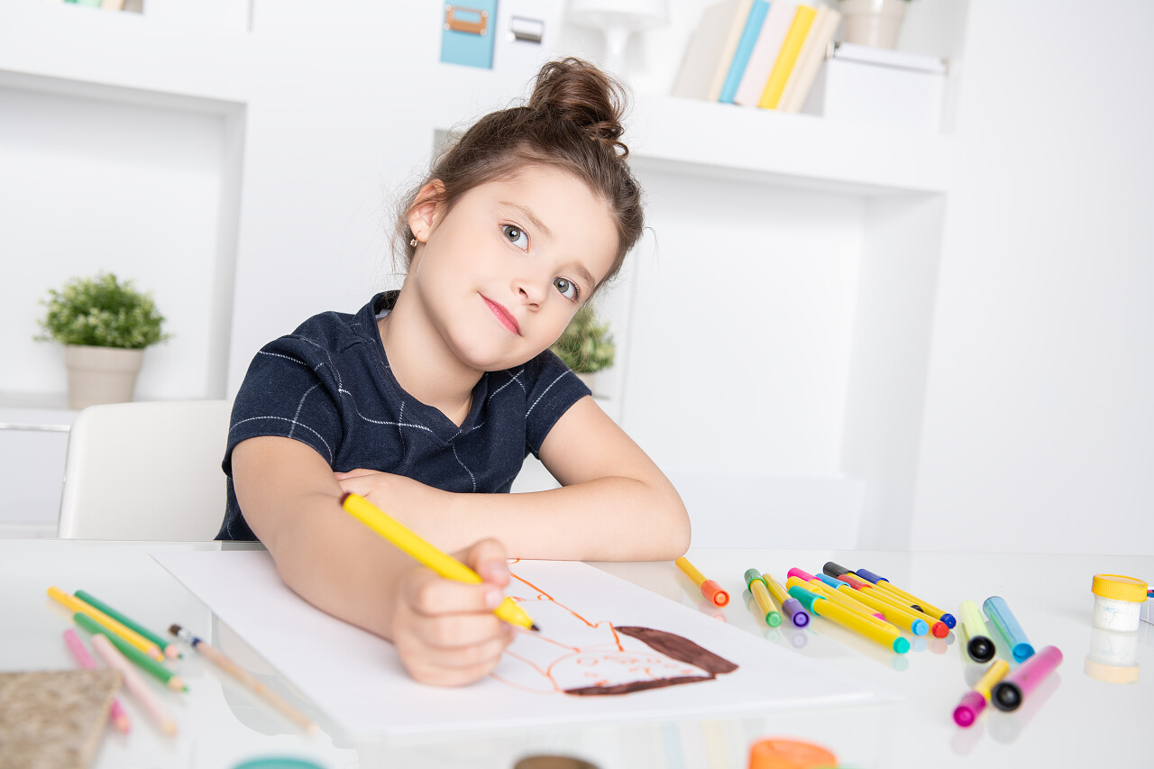 一个漂亮可爱的女孩坐在桌旁画画