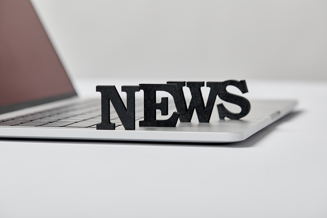 在灰色的笔记本电脑附近的黑色新闻字母