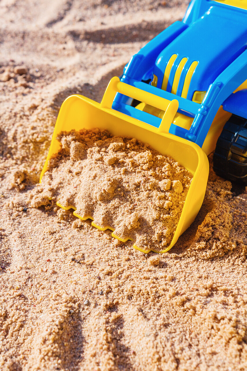 沙盒和儿童塑料蓝与黄色挖掘机儿童户外游戏的概念