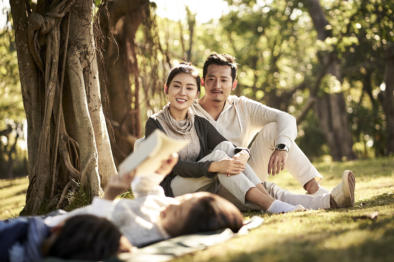 两个亚洲孩子小男孩和女孩躺在草地上看一本书