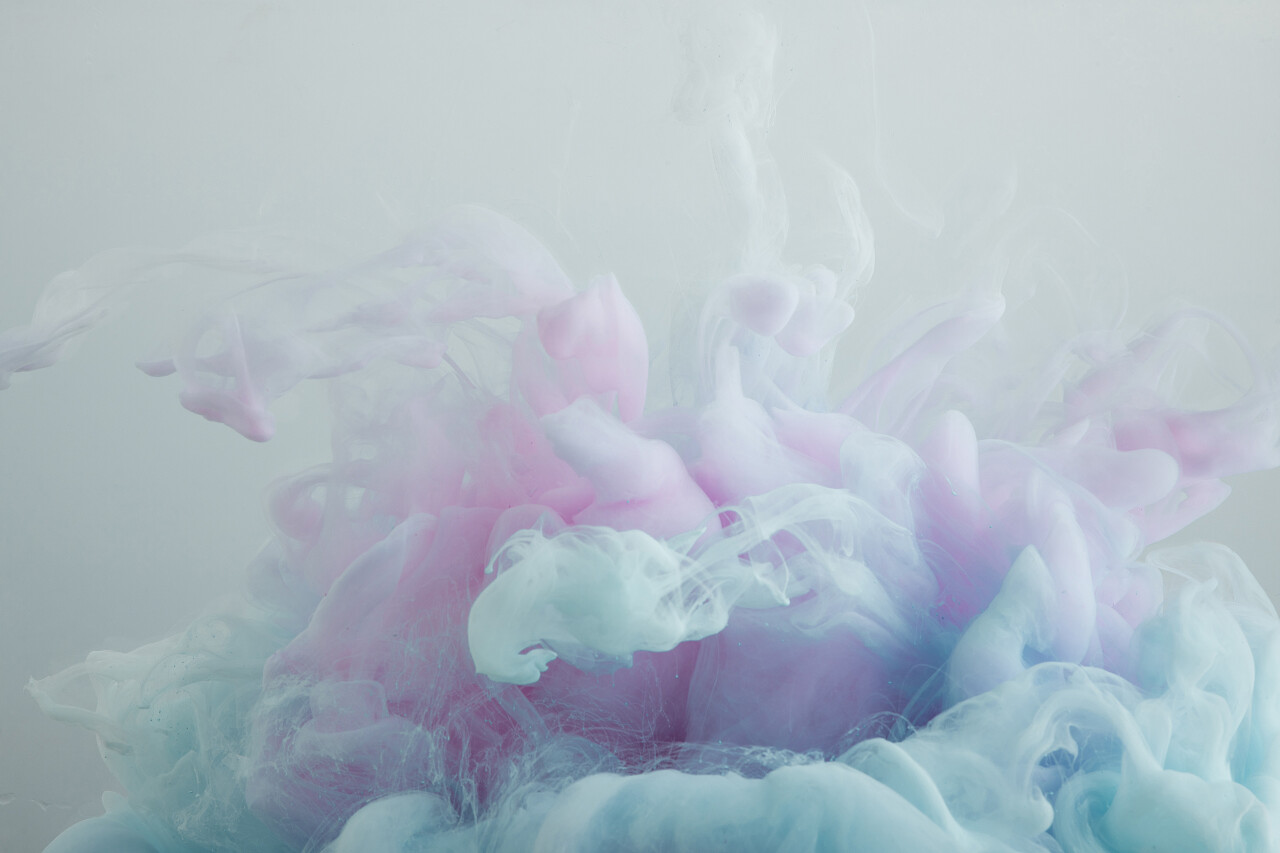 浅蓝色和粉红色油漆漩涡的特写视图隔离在灰色上