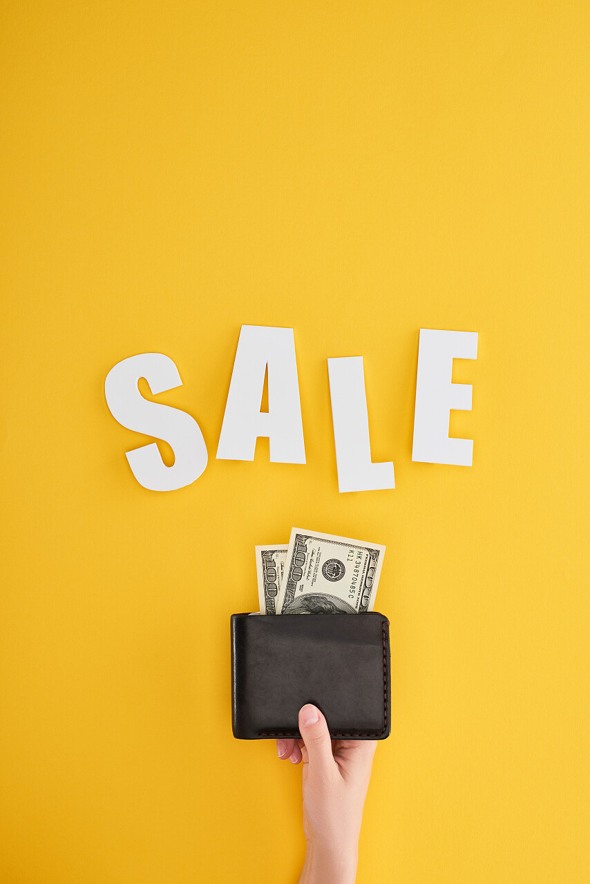 持有黄色背景并附有销售信笺的妇女钱包的偏视