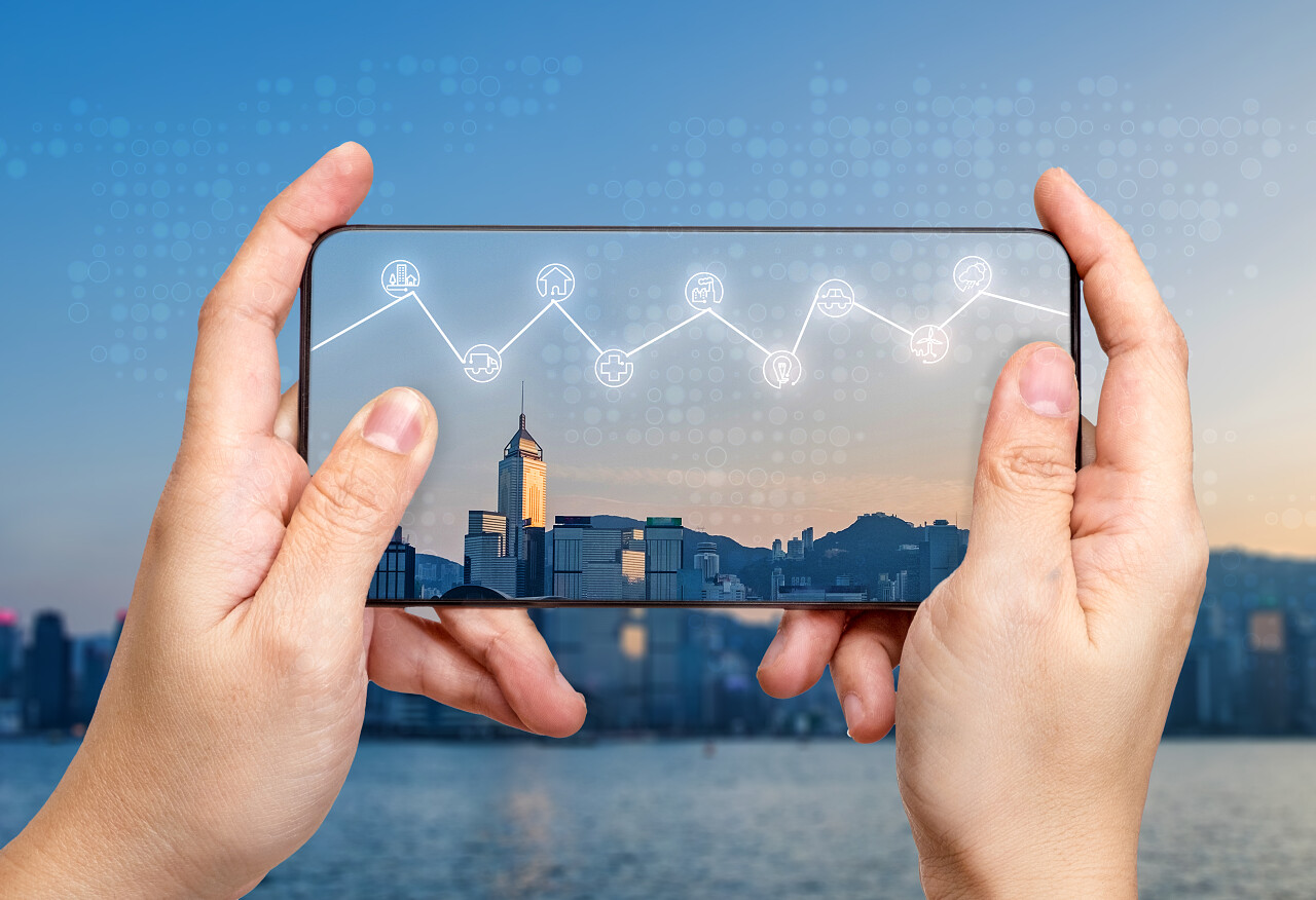 手持移动与互联网的东西字在屏幕上的图标功能在空气中闪耀与模糊城市建设背景, 数字生活方式概念.