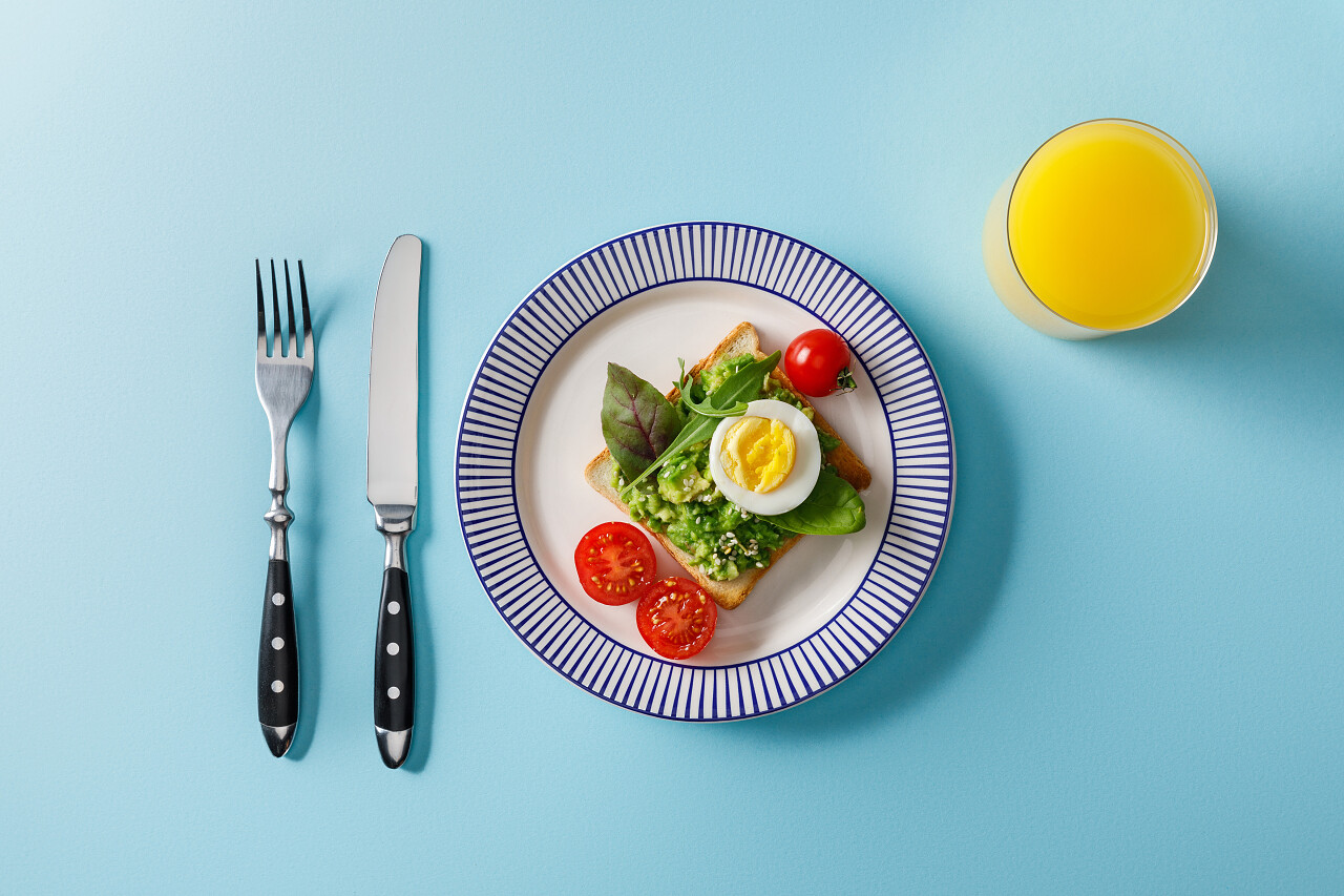 供应早餐的顶视图烤面包与瓜卡莫莱和橙汁的蓝色背景