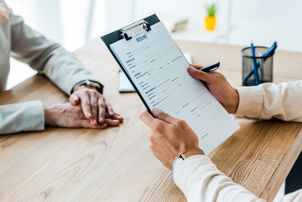 员工在招聘人员附近拿着带有简历信的裁剪视图