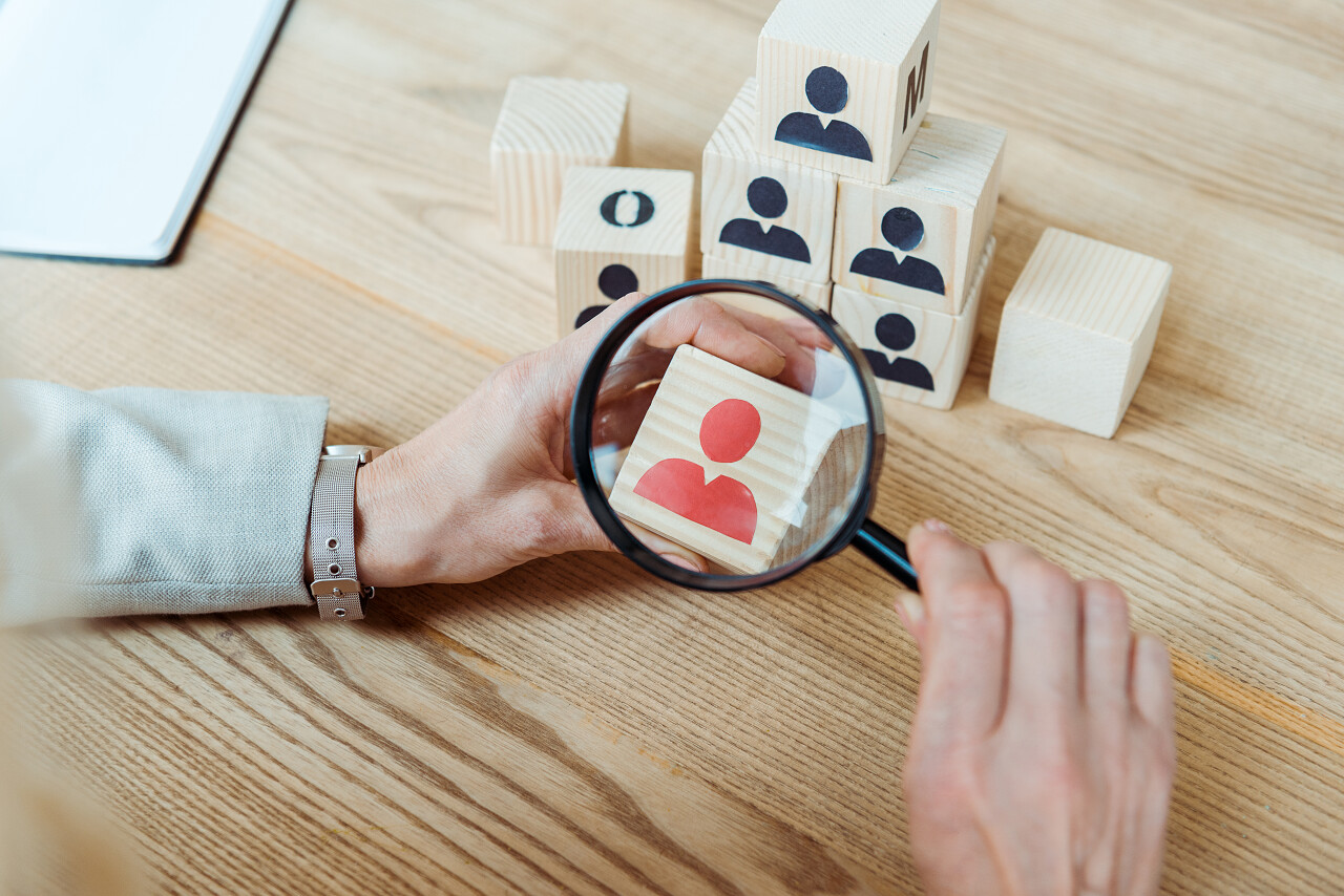 招聘在木立方体附近拿着放大镜的妇女的裁剪视图