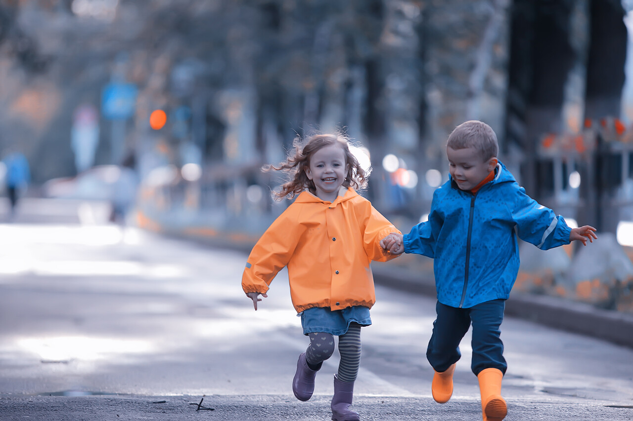 穿着雨衣的孩子在雨中在外面玩耍照片