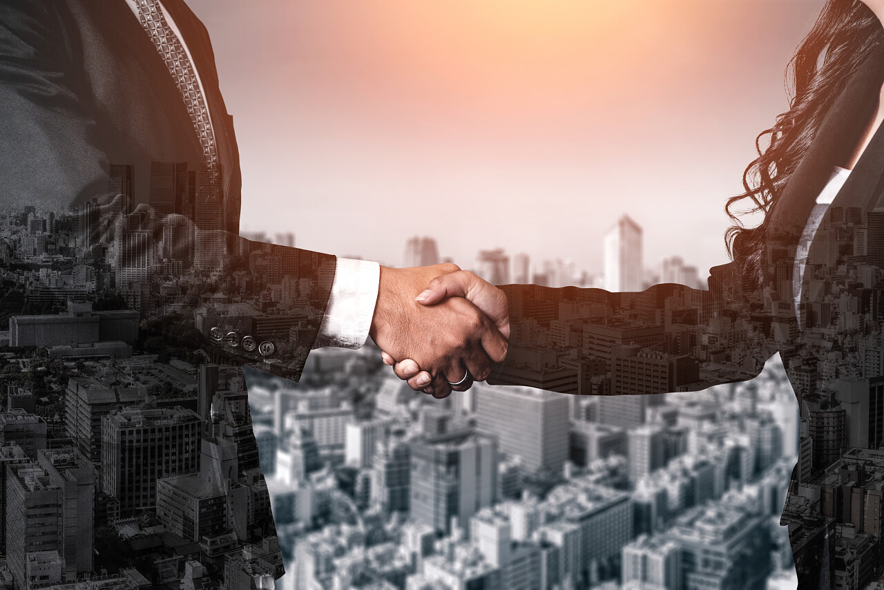 商业人士在城市办公楼上握手的双重曝光图像合作团结握手企业团结团结人物合作平台