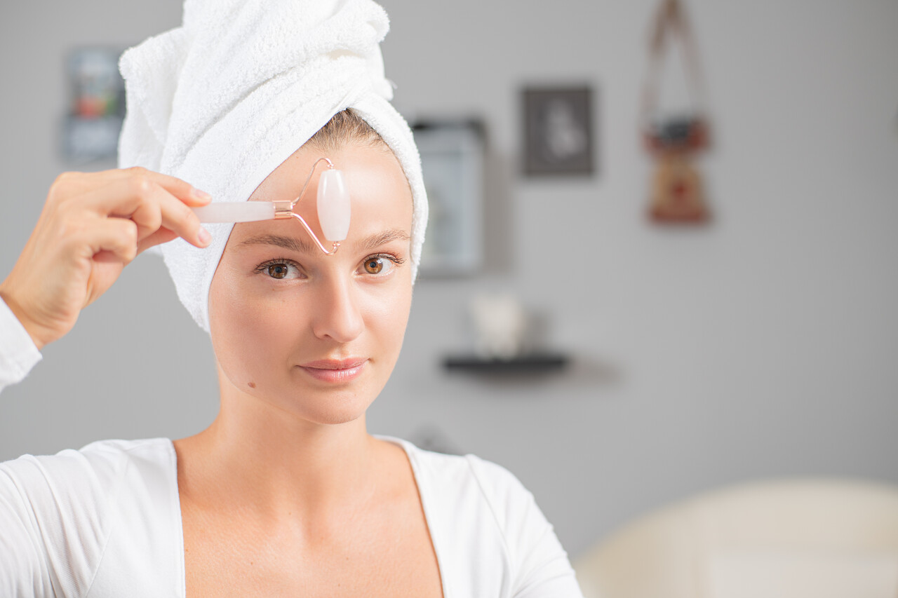 面部按摩美丽的女人得到按摩脸使用玉面辊皮肤护理面部清洁脸部