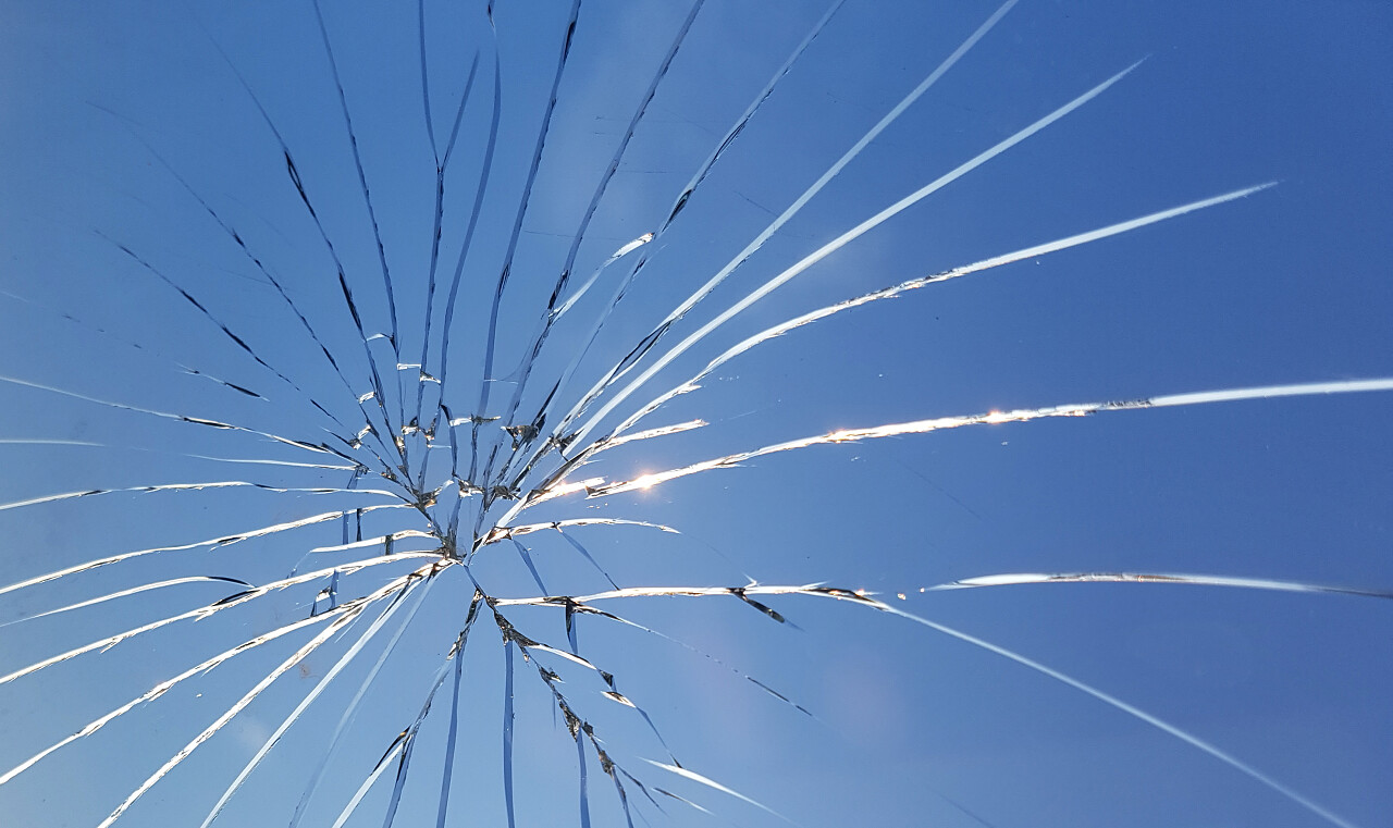 蓝天背景上有裂缝的碎玻璃