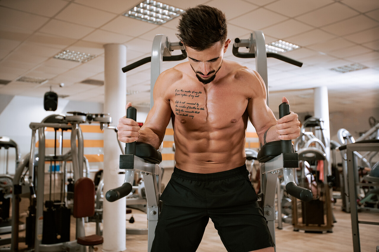 无衬衫肌肉的年轻人做杠铃板凳在健身房的压榨练习