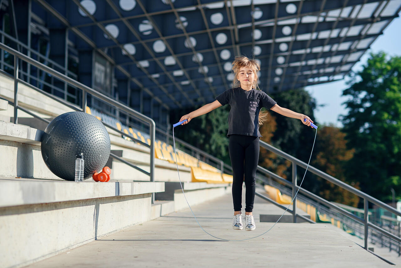 年轻女学生在体育场外面跳着跳绳