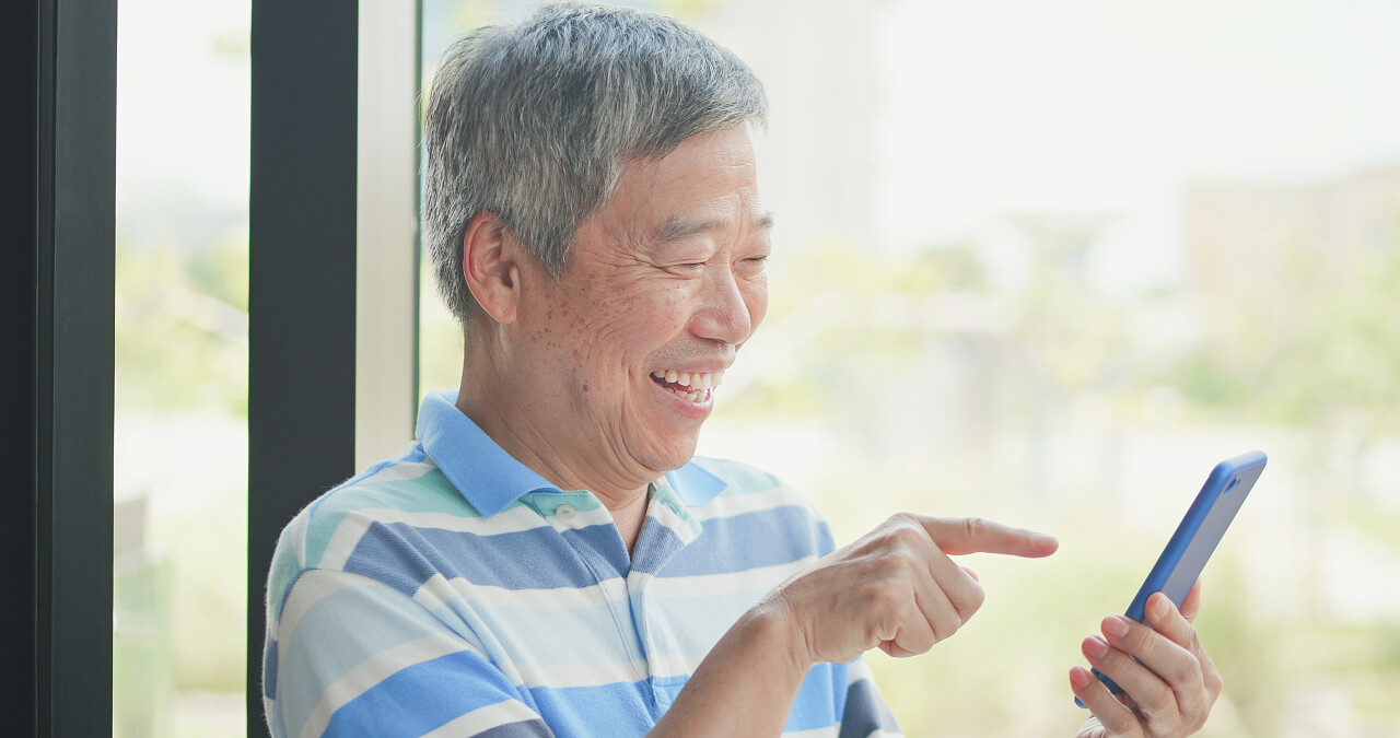 老人使用智能手机在窗口