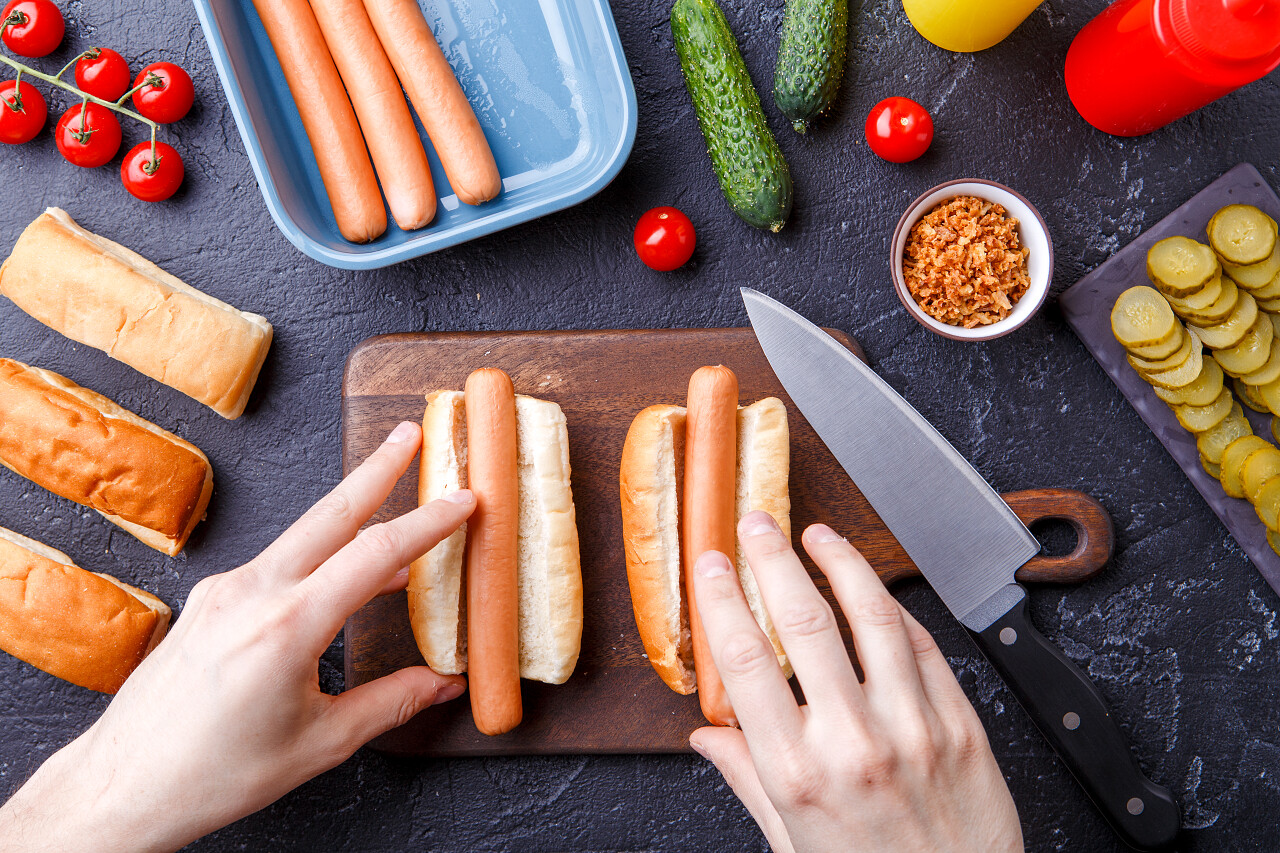 人们在桌上用切菜板做热狗