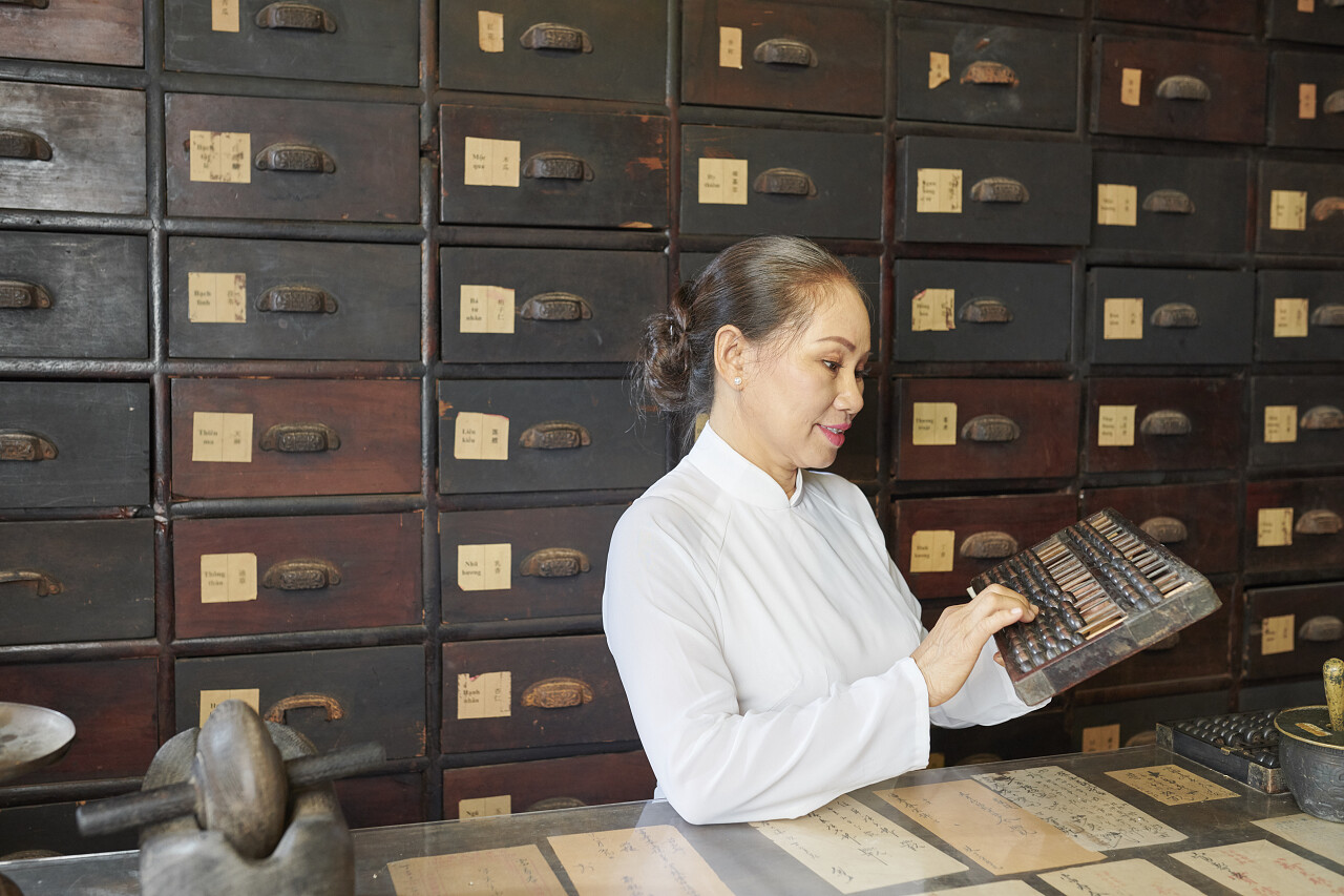 成熟的亚洲女人在与传统的中国药剂师对质时依靠算盘