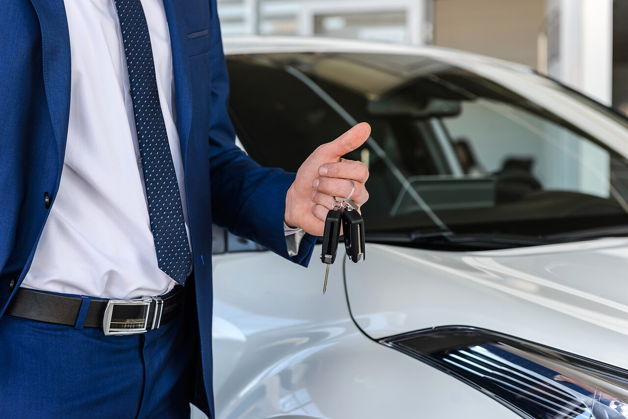手拿车钥匙在新车旁
