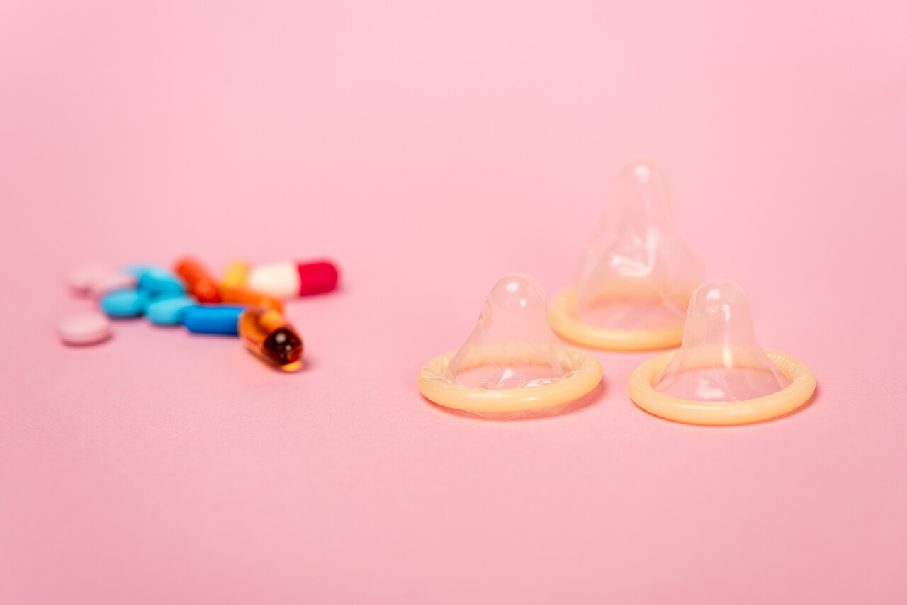 粉色背景的避孕套和节育丸的选择性重点