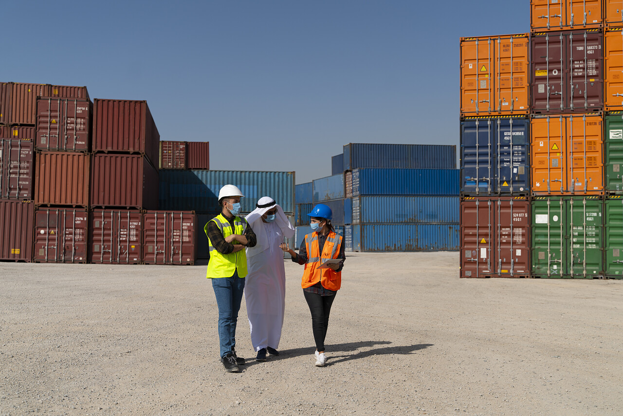 中东商人和戴口罩的工程师在外面的一个大型商业码头上工作