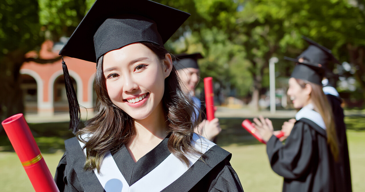 毕业季人物大学毕业季毕业季人像快乐的女研究生手握毕业文凭面带微笑