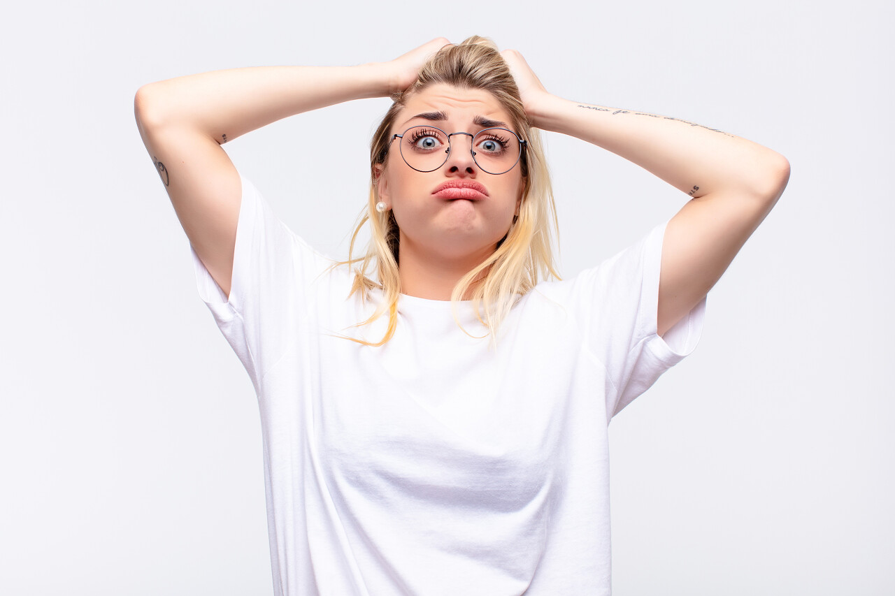 年轻漂亮的金发女人感到沮丧烦恼厌倦了失败厌倦了白墙旁枯燥无味的工作沮丧人物烦躁恼火烦躁暴躁