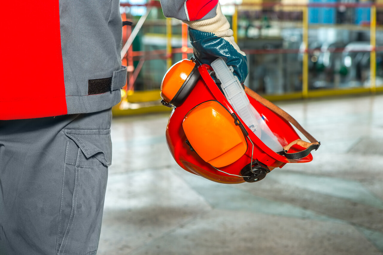 一个工人工厂的背景下拿着安全帽