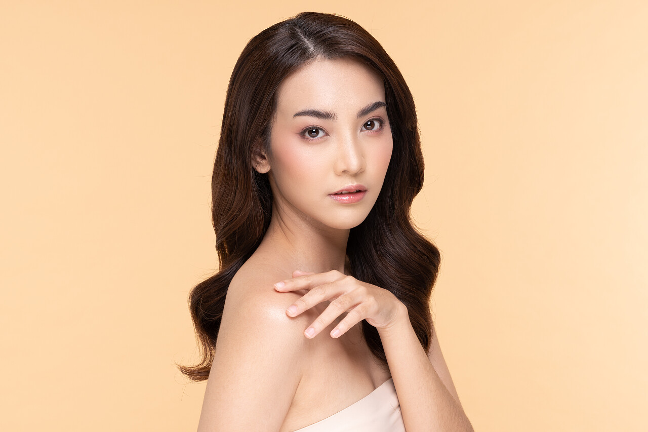 美丽的年轻亚洲女人一边摸着肩膀一边又开心又快乐有着健康的洁净而新鲜的皮肤有着米色的背景美女三七女生节37女生节三八妇女节38妇女节