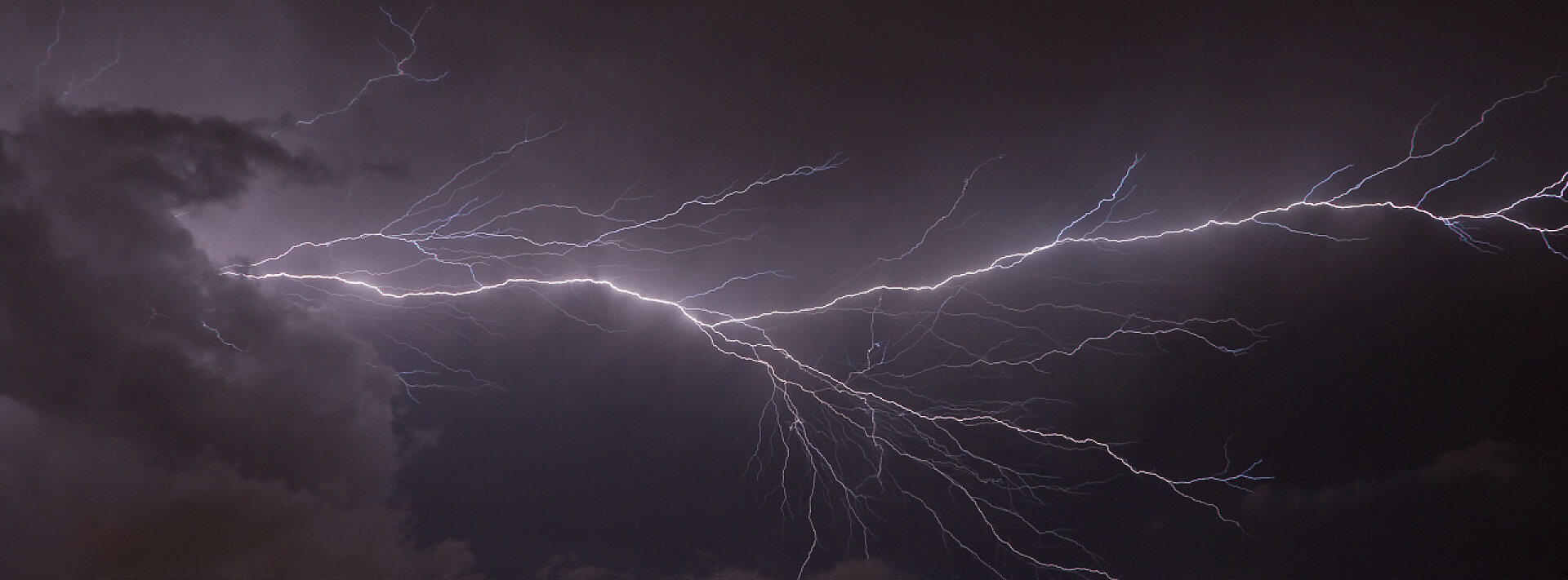 阴暗的天空上闪耀着紫色的雷电闪电横幅