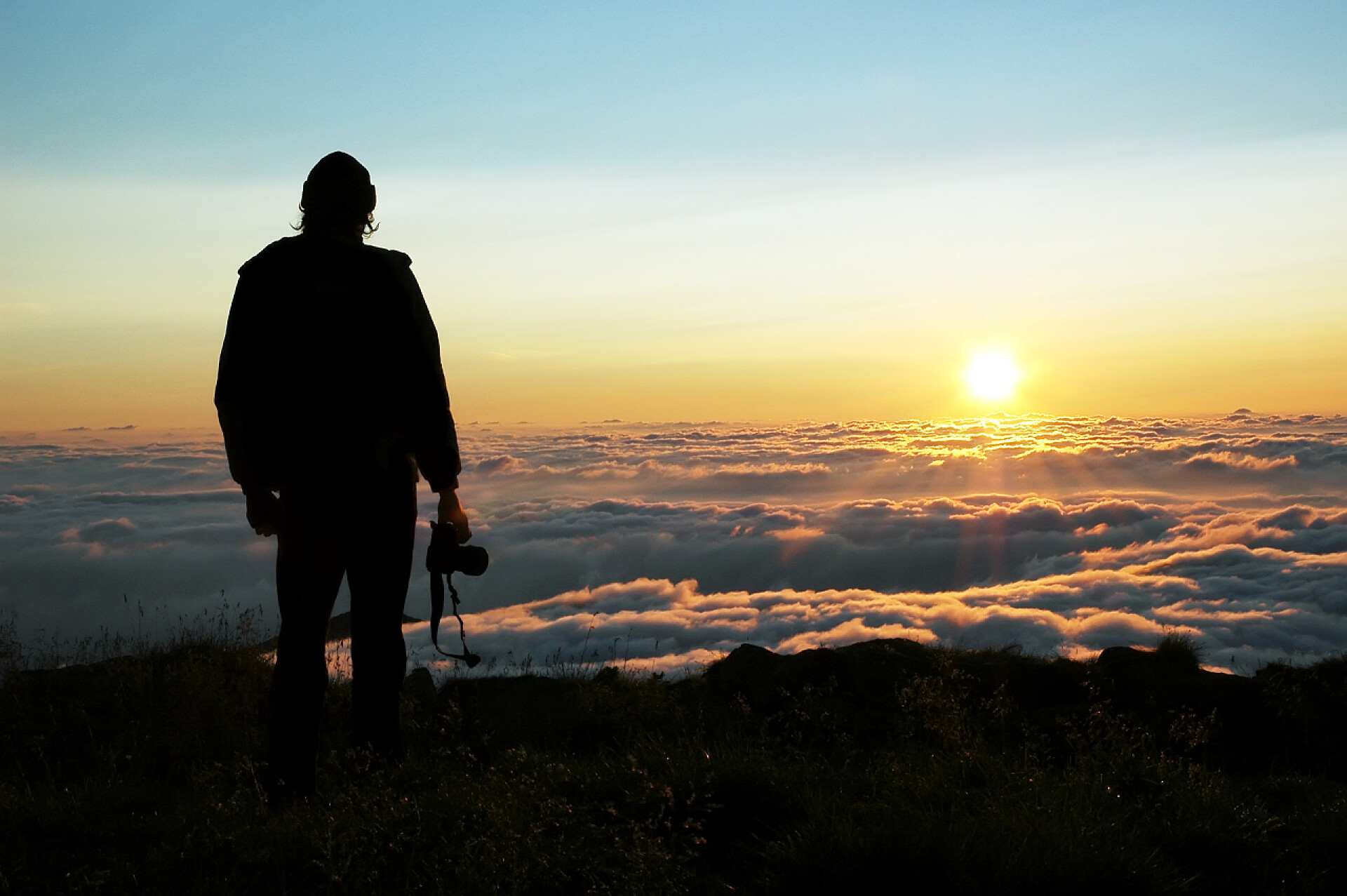 夕阳下一位摄影师站在山峰上的剪影在山中的黎明