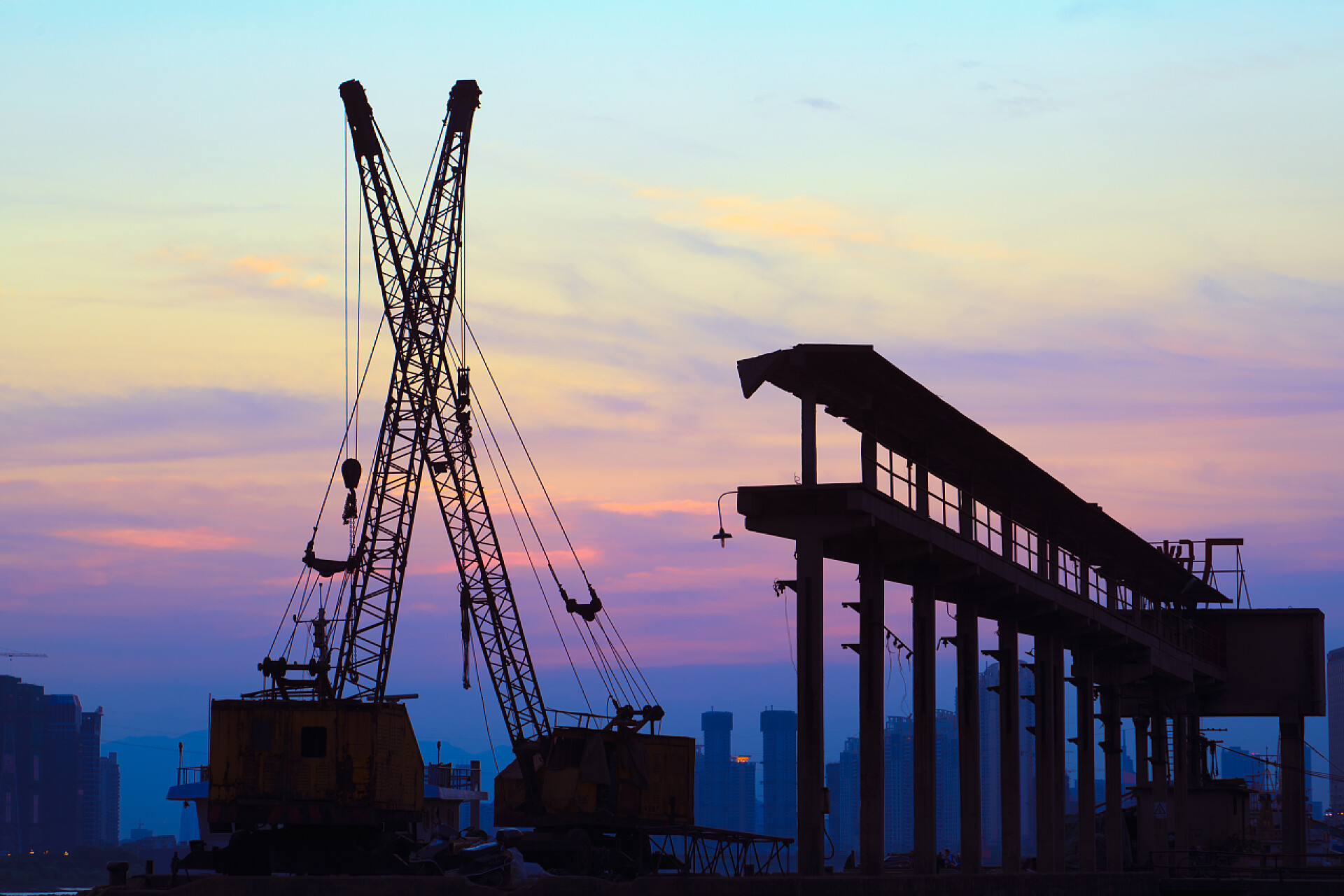 日落时几个起重机在港工作的剪影起重机在日落时工作